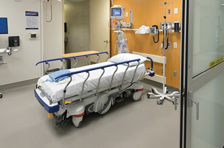 Photo of an unoccupied ED room shows a bed, monitor, IV pole, and other equipment.